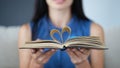 In female hands, book sheets are folded in shape of heart closeup Royalty Free Stock Photo