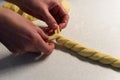 Female hands braiding dough on white kitchen table, close up Royalty Free Stock Photo