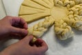 Female hands braiding dough on white working kitchen table, close up Royalty Free Stock Photo