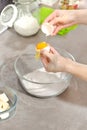 Female hands while breaking the chicken egg. Separation of the yolk from the protein. Adding an egg to the ingredients prepared to