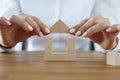 Female hands build house from wooden cubes.