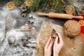 Female hands carve Christmas cookies figures in a christmas tree shape on a kitchen wooden table, top view. Christmas mood backgr