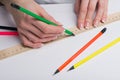 Female hands with classical French manicure draw a pencil by means of a ruler on clean standard sheet