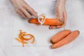 Female hands clean carrots with a vegetable peeler.Cleaning vegetables