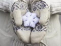 Female hands close up in knitted wore mittens holding white snowflake outdoors.