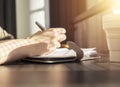 Female hands closeup taking notes in notebook. Woman sitting at table with collapsible silicon mug and writing agenda or