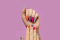 Female hands with colorful nail design. Glitter nail polish manicure: purple, green, pink and orange on pink background Royalty Free Stock Photo