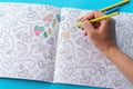 Female hands coloring anti stresss color book with hearts and flowers pattern. Art therapy concept. Healthy lifestyle, leisure.