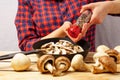 Female hands of the cook sprinkle spices on mushrooms in a frying pan