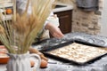 The female hands of the cook sprinkle sugar on puff pastry lying on parchment on a baking sheet at home in the kitchen. Nearby lie