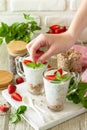 Female hands cooking healthy eating concept breakfast. Homemade granola with strawberry, yogurt, chia seeds, homemade granola. Royalty Free Stock Photo