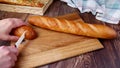 Female hands cut bread baguette on a wooden cutting board Royalty Free Stock Photo