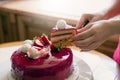 Female hands cut an appetizing pink mousse cake, side view