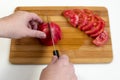 Female hands cut on a board of tomatoes