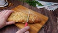 Female hands cut with a bread baguette with cheese on cutting board Royalty Free Stock Photo