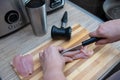 Female hands cut chicken fillet on wooden board with a knife Royalty Free Stock Photo