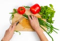 Female hands cut green onions with knife on wooden board. Colorful vegetables. White background