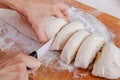 Female hands cut with a knife a kneaded dough on a wooden board. Homemade cooking. Royalty Free Stock Photo