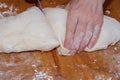 Female hands cut with a knife a kneaded dough on a wooden table Royalty Free Stock Photo