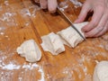 Female hands cut with a knife a kneaded dough on a wooden table Royalty Free Stock Photo