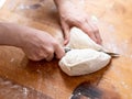 Female hands cut with a knife a kneaded dough on a wooden table Royalty Free Stock Photo