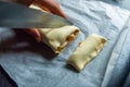 Female hands cut the rolled puff pastry into equal pieces. In the middle, there is a pepper, ham, garlic sauce, and corn. Royalty Free Stock Photo