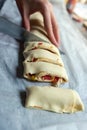 Female hands cut the rolled puff pastry into equal pieces. In the middle, there is a pepper, ham, garlic sauce, and corn. Royalty Free Stock Photo