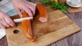 Female hands cut smoked sausage on a cutting board