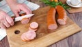 Female hands cut smoked sausage into slices on a cutting board Royalty Free Stock Photo