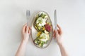 Female hands with cutlery near the plate with toast made with microgreens, poached eggs, avocado, asparagus and cheese. Royalty Free Stock Photo