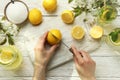 Female hands cuts lemon for making lemonade on white wooden background