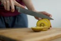 Female hands is cutting a fresh ripe golden kiwi fruit on a cut wooden board. Exotic fruits, healthy eating concept Royalty Free Stock Photo