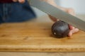 Female hands is cutting a fresh ripe passion fruit, maracuya on a cut wooden board. Exotic fruits, healthy eating Royalty Free Stock Photo