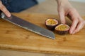 Female hands is cutting a fresh ripe passion fruit, maracuya on a cut wooden board. Exotic fruits, healthy eating Royalty Free Stock Photo