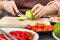 Female hands cutting green lime on wooden cutting board in her h Royalty Free Stock Photo