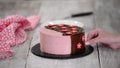 Female hands decorate homemade strawberry mousse cake with sugar flowers.