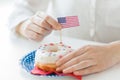 Female hands decorating donut with american flag