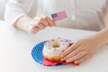 Female hands decorating donut with american flag