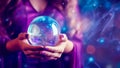 Female hands delicately holding glowing crystal ball on magic purple backdrop Royalty Free Stock Photo