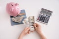 Female hands with dollars, piggy bank, wallet and calculator on white background, top view