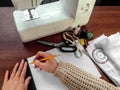 Female hands draw with a pencil and a ruler on a white sheet of paper on the background of sewing supplies. The concept of Royalty Free Stock Photo