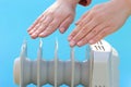 Female hands on electric oil radiator on blue background Royalty Free Stock Photo