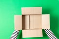 Female hands with empty open cardboard boxes on light green background. Top view Royalty Free Stock Photo