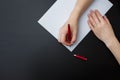 Female hands with fir-tree forest manicure holding red pen over white paper on black background. Christmas or winter nail art. Royalty Free Stock Photo