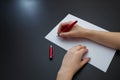 Female hands with fir-tree forest manicure holding red pen over white paper on black background. Christmas or winter nail art. Royalty Free Stock Photo