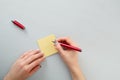 Female hands with fir-tree forest manicure holding red pen over yellow paper stickers. Christmas or winter nail art. Hands care Royalty Free Stock Photo