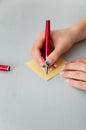 Female hands with fir-tree forest manicure holding red pen over yellow paper stickers. Christmas or winter nail art. Hands care Royalty Free Stock Photo