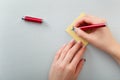 Female hands with fir-tree forest manicure holding red pen over yellow paper stickers. Christmas or winter nail art. Hands care Royalty Free Stock Photo