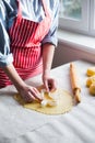 Female hands in flour making Christmas cookie in the form of gingerbread man from dough in daylight. Royalty Free Stock Photo