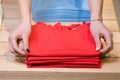 Female hands fold red shirts, clothing store